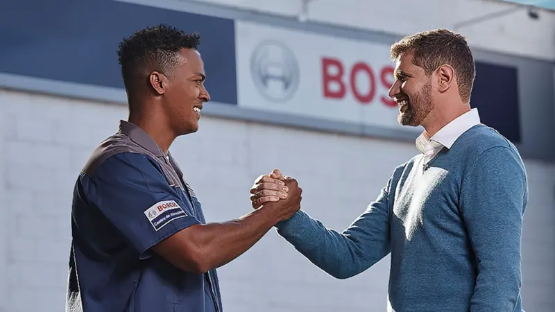 Um mecânico do Centro de Direção aperta a mão de um cliente.