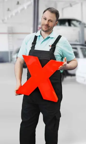 eXtra Tom stehend mit rotem x in Werkstatt