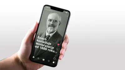 Zbliżenie na dłoń trzymającą smartfon. Na ekranie widoczny jest post w mediach społecznościowych z portretem Roberta Boscha i hasłem: „Jesteśmy motoryzacyjnymi influencerami od 1886 roku.”