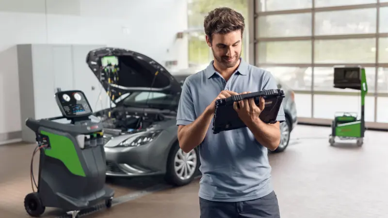 Ein Mechaniker in einer Kfz-Werkstatt nutzt Diagnosesoftware auf einem DCU 220 Gerät.