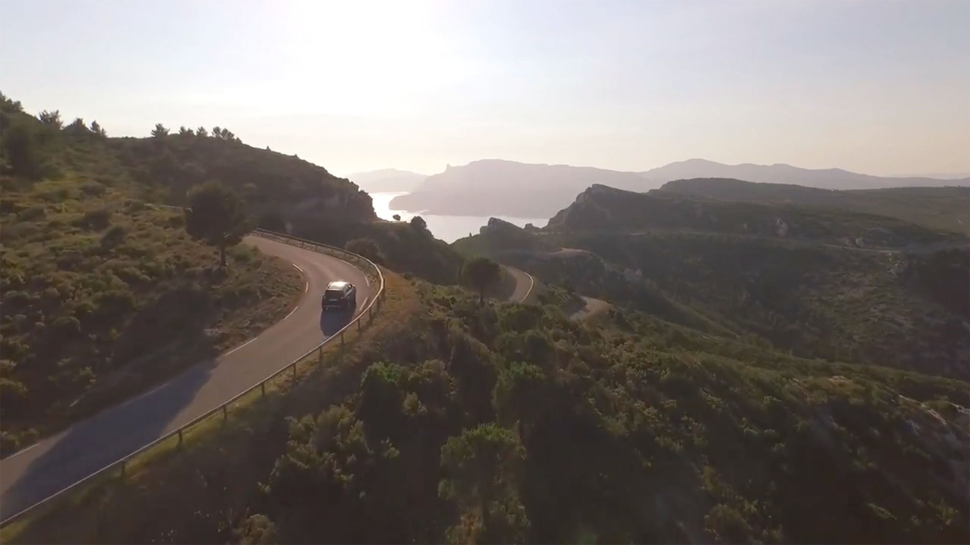 Vehicle drives on a sloping panoramic road in the middle of an idyllic landscape