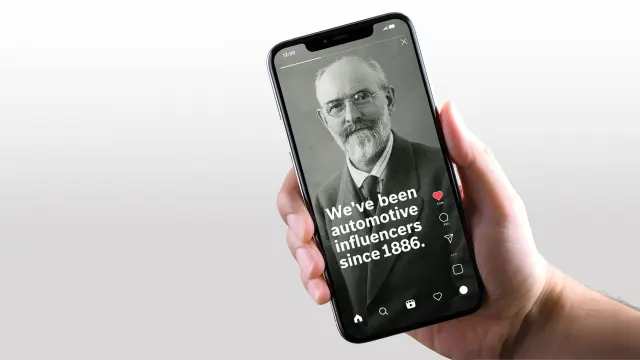 Detail ruky držící chytrý telefon zobrazující příspěvek ze sociálních médií s historickým portrétem Roberta Bosche a textem „We've been automotive influencers since 1886.“